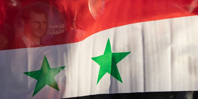 In this May 23, 2021, file photo, the Syrian flag is displayed at a gathering at Omayyad Square in the Syrian capital Damascus, Syria.