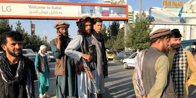 A member of Taliban (C) stands outside Hamid Karzai International Airport in Kabul, Afghanistan, August 16. REUTERS/Stringer