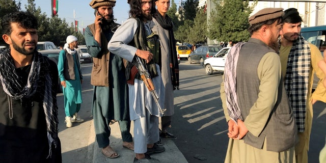 A member of Taliban (C) stands outside Hamid Karzai International Airport in Kabul, Afghanistan, August 16. REUTERS/Stringer