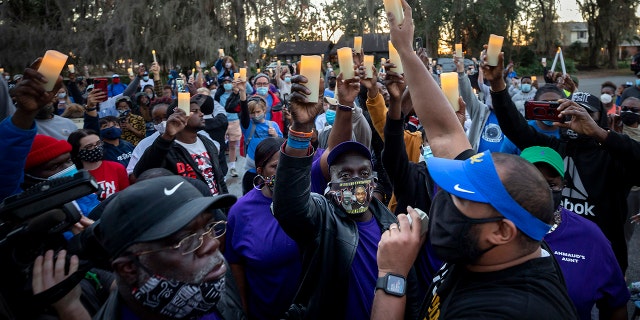 In this photo from February, Ahmaud Arbery's father, Marcus Arbery, bottom center, listens to Jason Vaughn speak during a memorial walk and candlelight vigil for Ahmaud at the Satilla Shores development in Brunswick, Georgia.