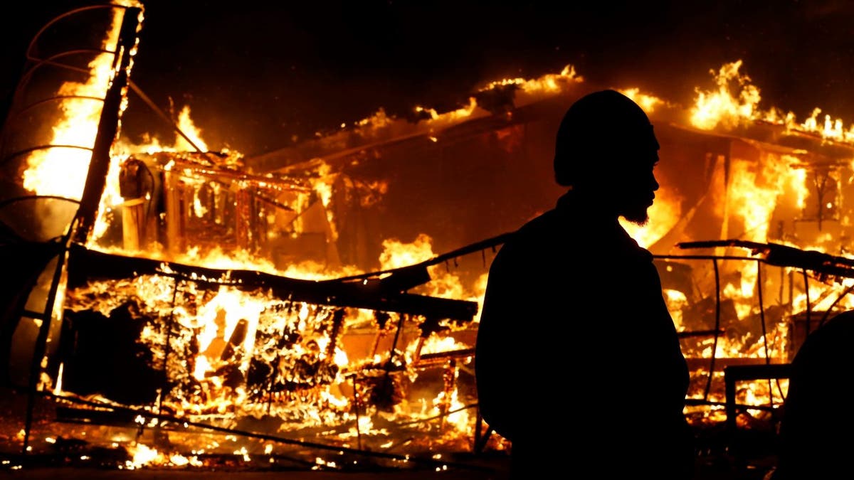 A man watches a burning building after a grand jury returned no indictment in the shooting of Michael Brown in Ferguson, Missouri November 24, 2014.   REUTERS/Jim Young