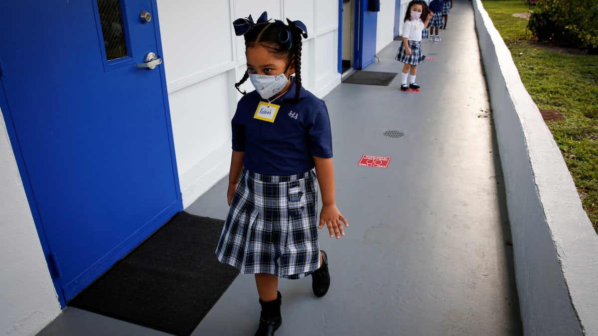 Students wearing a protective mask, queue up outside classrooms on the first day of school, amid the coronavirus disease (COVID-19) pandemic, at St. Lawrence Catholic School in North Miami Beach, Florida, U.S. August 18, 2021. REUTERS/Marco Bello TPX IMAGES OF THE DAY