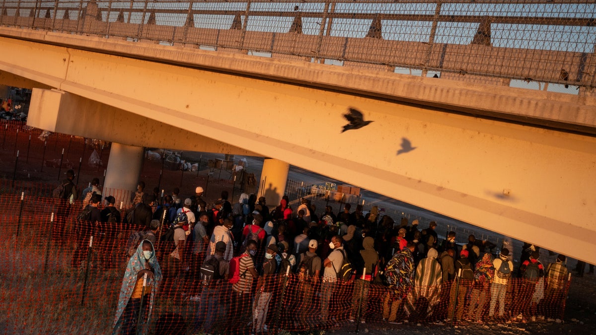 FILE PHOTO: A bird flies past migrants as they await at sunrise to be transported out of a border makeshift camp along the International Bridge in Del Rio, Texas, U.S. September 24, 2021. Picture taken with a drone. REUTERS/Adrees Latif/File Photo