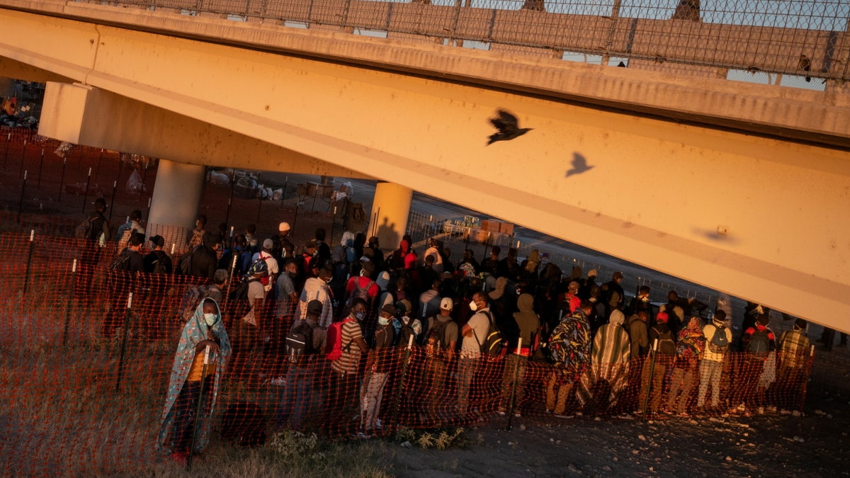 FILE PHOTO: A bird flies past migrants as they await at sunrise to be transported out of a border makeshift camp along the International Bridge in Del Rio, Texas, U.S. September 24, 2021. Picture taken with a drone. REUTERS/Adrees Latif/File Photo