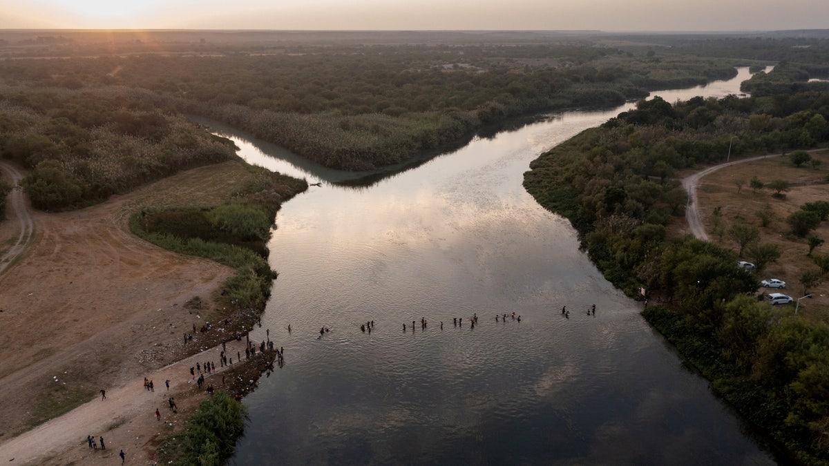 FILE PHOTO: Migrants seeking refuge in United States cross the Rio Grande river, with bags and children in tow, back into Ciudad Acuna, Mexico from their camp in Del Rio, Texas, U.S. September 21, 2021. Picture taken with a drone. REUTERS/Adrees Latif//File Photo