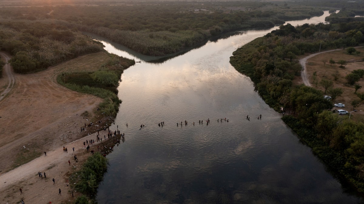 Migrants seeking refuge in United States cross the Rio Grande River back into Mexico from their camp in Del Rio, Texas, on Sept. 21, 2021.