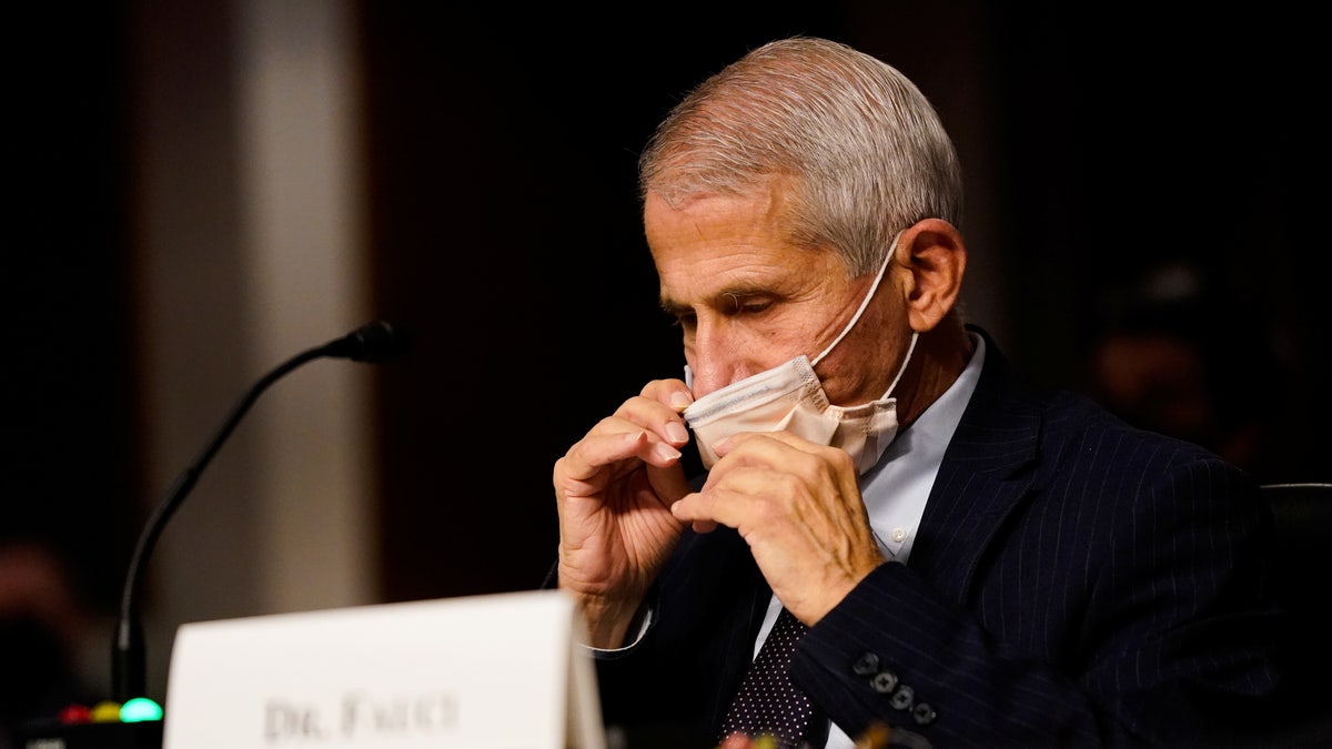 White House Chief Medical Adviser Dr. Anthony Fauci adjusts his mask 