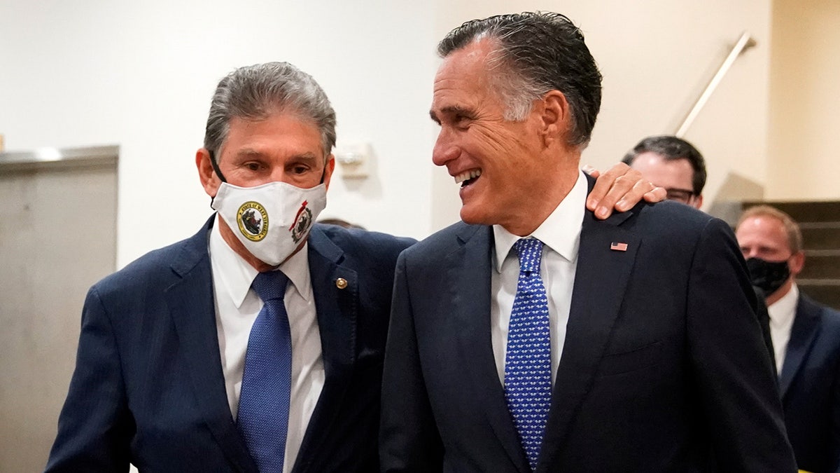 U.S. Senator Joe Manchin (D-WV) puts his arm over U.S. Senator Mitt Romney's (R-UT) shoulder as they walk through the Senate subway at the U.S. Capitol in Washington, U.S., November 4, 2021. REUTERS/Elizabeth Frantz