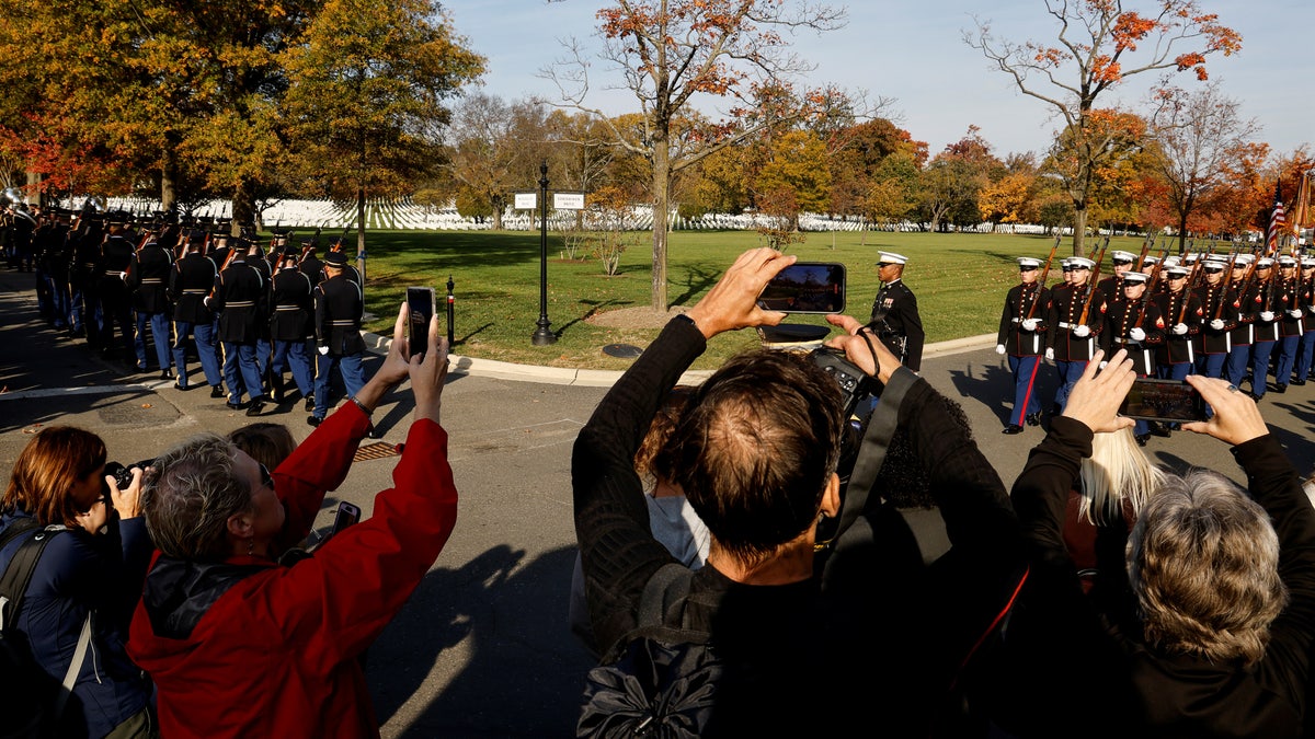 People snap pictures as U.S. troops march during a joint full honors procession evoking the original 1921 funeral procession of a World War I unknown soldier, in commemoration of the 100th anniversary of the Tomb of the Unknown Soldier on Veterans Day in Arlington National Cemetery in Arlington, Virginia, U.S., November 11, 2021. REUTERS/Jonathan Ernst/Pool