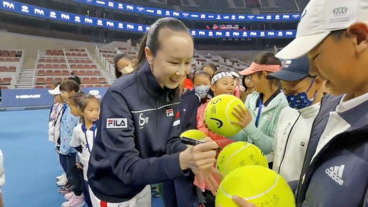 Chinese tennis player Peng Shuai signs large-sized tennis balls at the opening ceremony of Fila Kids Junior Tennis Challenger Final in Beijing, China, on Nov. 21, 2021.