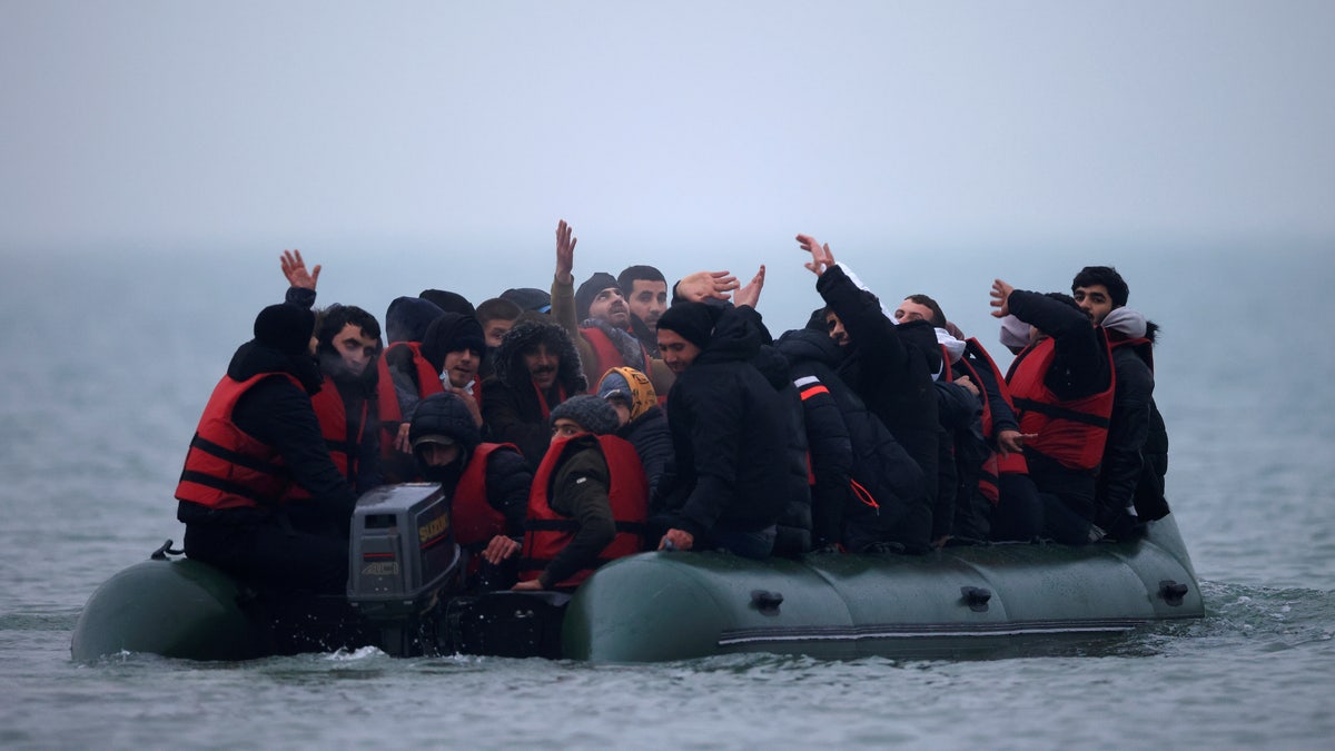 A group of more than 40 migrants react as they succeeded to get on an inflatable dinghy, to leave the coast of northern France and to cross the English Channel, near Wimereux, France, November 24, 2021. REUTERS/Gonzalo Fuentes