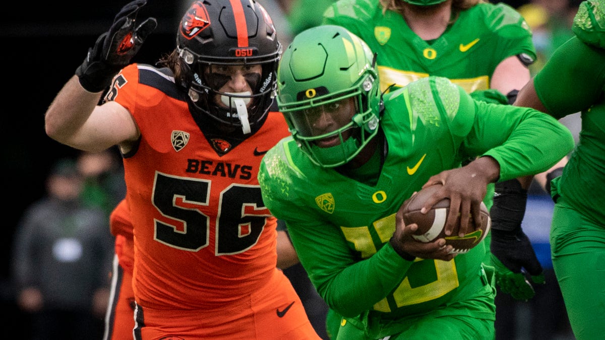 Oregon quarterback Anthony Brown (13) tries to elude the tackle of Oregon State linebacker Riley Sharp (56) during the second quarter of an NCAA college football game Saturday, Nov. 27, 2021, in Eugene, Oregon.