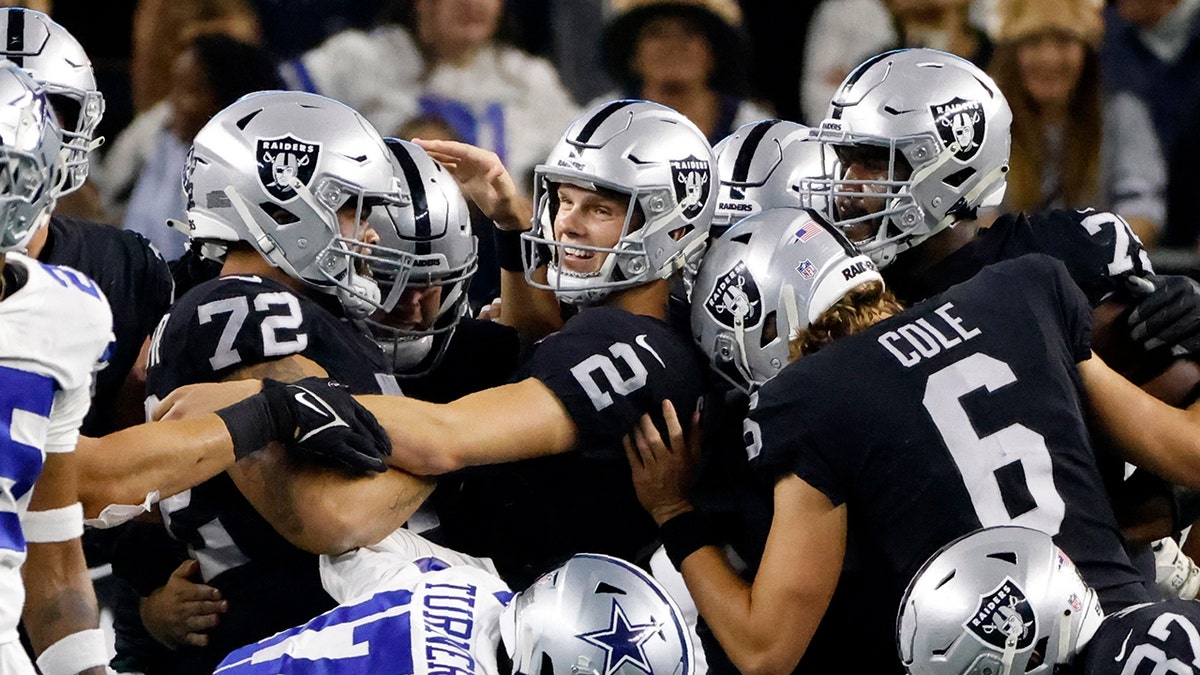 Las Vegas Raiders place kicker Daniel Carlson (2) is congratulated by Jermaine Eluemunor (72), AJ Cole (6) and others after Carlson kicked a game-winning field goal in overtime of an NFL football game against the Dallas Cowboys in Arlington, Texas, Thursday, Nov. 25, 2021.