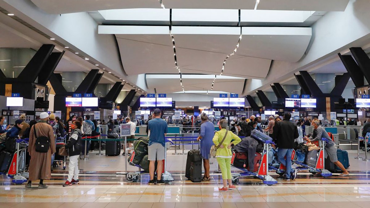 Travelers queue at a check-in counter at OR Tambo International Airport in Johannesburg, South America, on Nov. 27, 2021, after several countries banned flights from South Africa following the discovery of a new COVID-19 variant omicron.