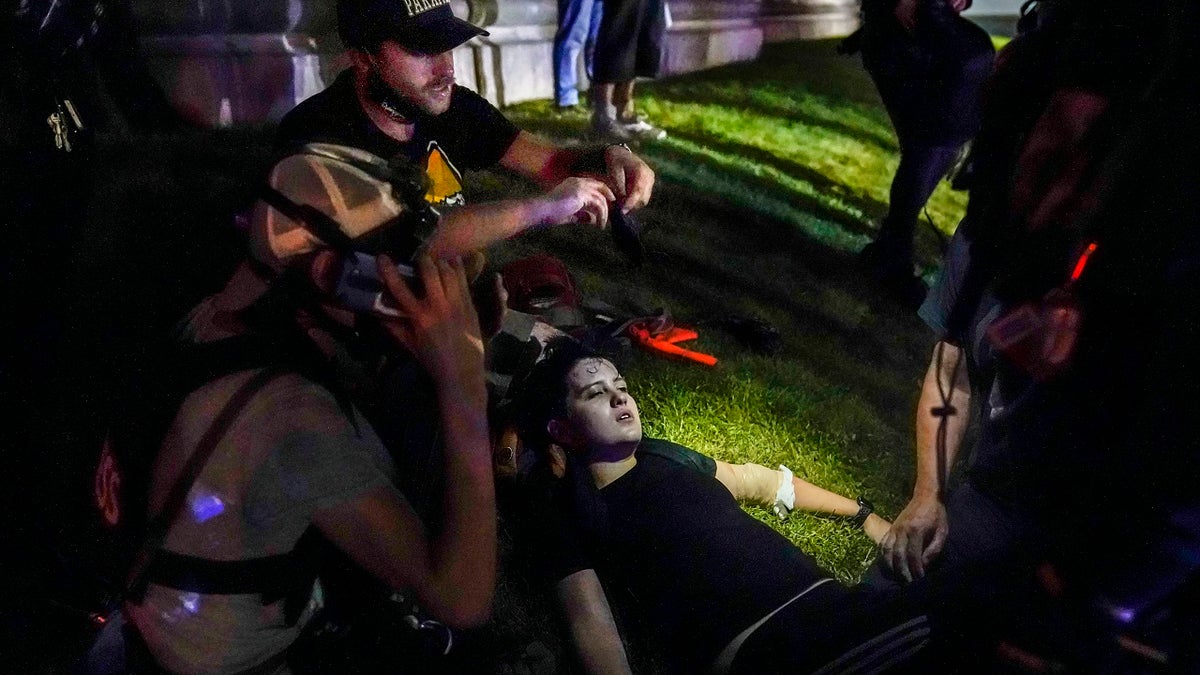 In this Aug. 25, 2020 file photo, Gaige Grosskreutz, top, tends to an injured protester during clashes with police outside the Kenosha County Courthouse