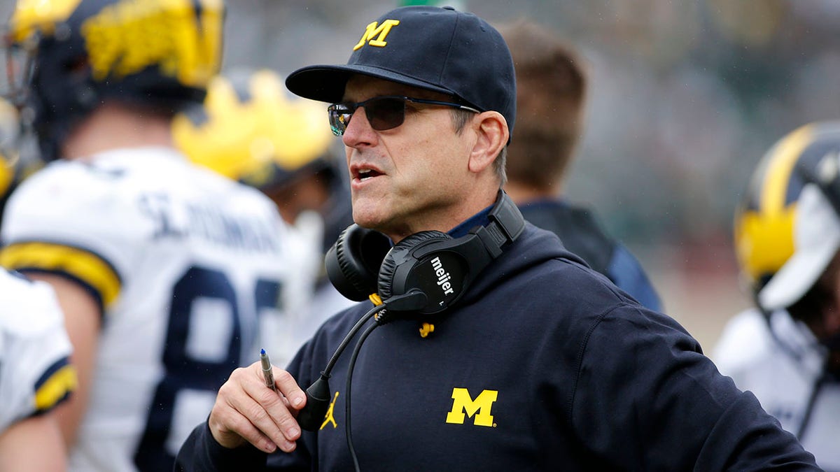 Michigan coach Jim Harbaugh watches during an NCAA college football game against Michigan State, Saturday, Oct. 30, 2021, in East Lansing, Mich. Michigan State won 37-33.