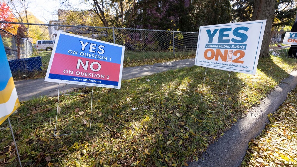 Lawn signs conflict with each other outside of a polling place on Tuesday in Minneapolis. (AP Photo/Christian Monterrosa)