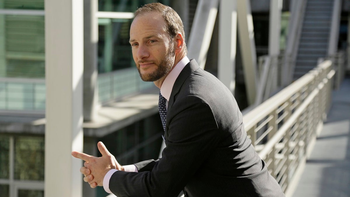 Chesa Boudin leans on a railing in a suit