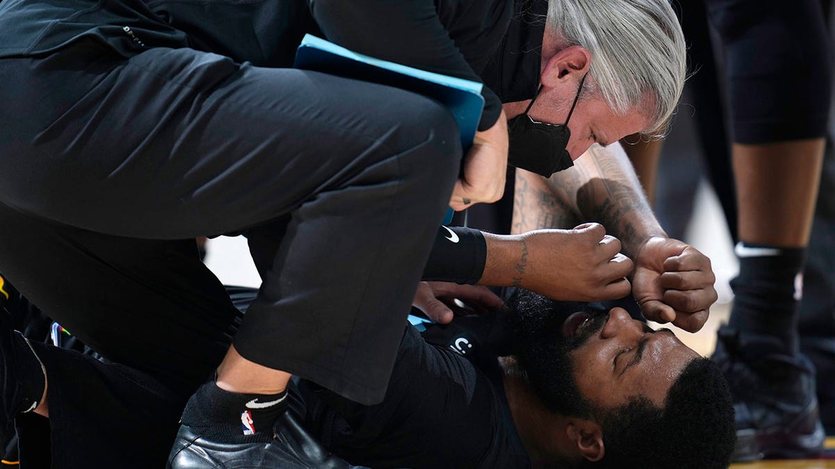 Miami Heat forward Markieff Morris, bottom, is attended to after being in an altercation with Denver Nuggets center Nikola Jokic in the second half of an NBA basketball game Monday, Nov. 8, 2021, in Denver. Morris walked off the court after being examined and Jokic was ejected. 