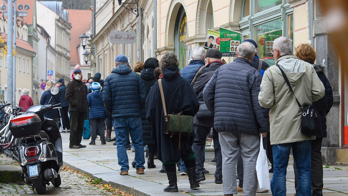 People wait in a long line to be vaccinated against the coronavirus during a vaccination campaign of the DRK, German Red Cross, in front of the town hall in Pirna, Germany, Monday, Nov. 15, 2021. (Robert Michael/dpa via AP)