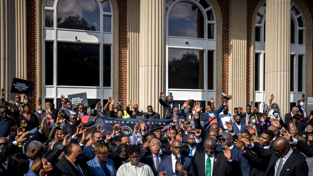 Pastor Jamal Bryant, bottom center, leads a group prayer for to nearly 750 pastors, supporters and family of Ahmaud Arbery gathered outside the Glynn County Courthouse during a Wall of Prayer event, Thursday, Nov. 18, 2021, in Brunswick, Ga. (AP Photo/Stephen B. Morton)