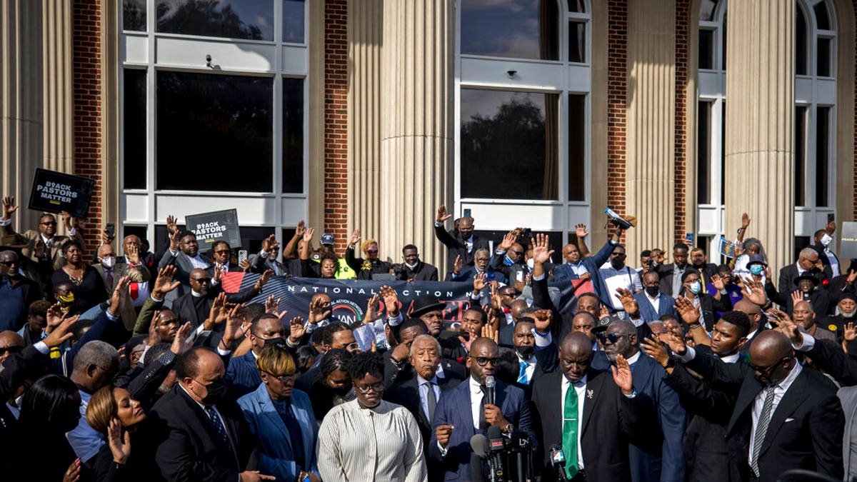 Pastor Jamal Bryant, bottom center, leads a group prayer for to nearly 750 pastors, supporters and family of Ahmaud Arbery gathered outside the Glynn County Courthouse during a Wall of Prayer event, Thursday, Nov. 18, 2021, in Brunswick, Ga. (AP Photo/Stephen B. Morton)