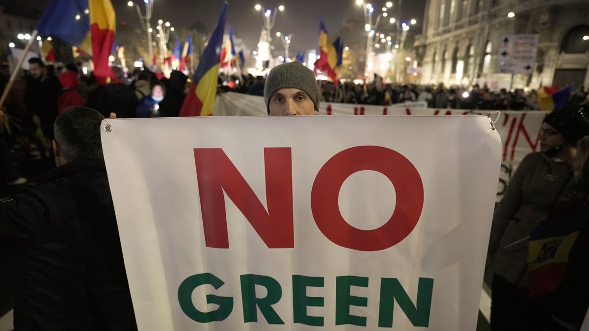 FILE - A man holds a banner during a protest against vaccinations, the introduction of the green pass and COVID-19 related restrictions in Bucharest, Romania, Sunday, Nov. 7, 2021. This was supposed to be the Christmas in Europe where family and friends could once again embrace holiday festivities and one another. Instead, the continent is the global epicenter of the COVID-19 pandemic as cases soar to record levels in many countries. With infections spiking again despite nearly two years of restrictions, the health crisis increasingly is pitting citizen against citizen — the vaccinated against the unvaccinated. (AP Photo/Vadim Ghirda, File)