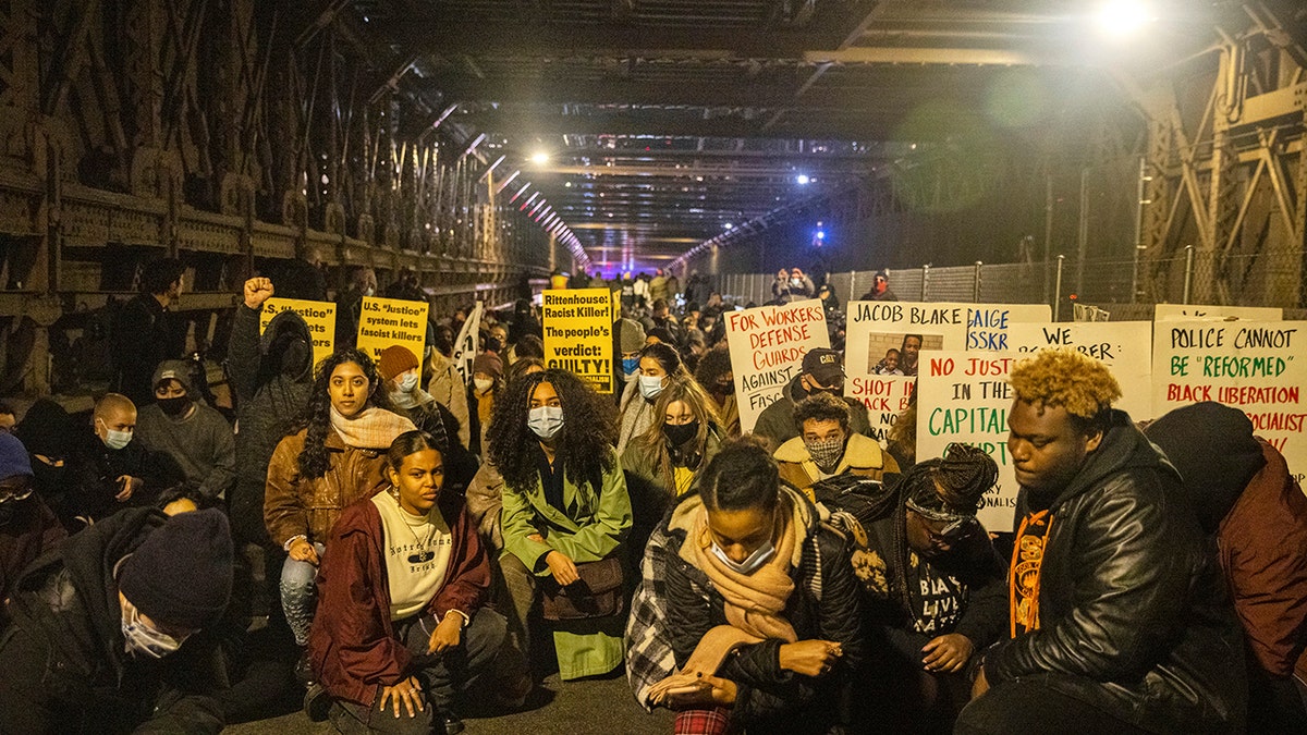 Protests kneel on the Brooklyn Bridge in New York City on Friday night. 