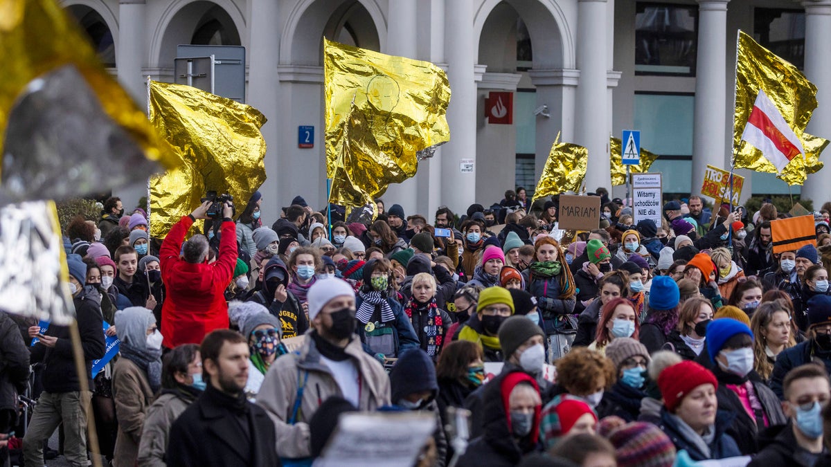 A few hundred people with banners and gold-and-silver hypothermia blankets march in Warsaw, Poland, on Saturday, Nov. 20, 2021, in support of the migrants stranded at the Belarus-Poland border. (AP Photo)