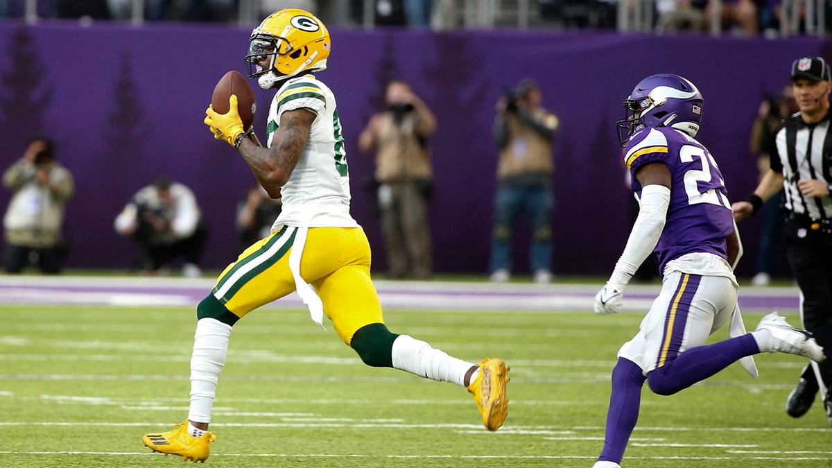 Green Bay Packers wide receiver Marquez Valdes-Scantling, left, catches a 75-yard touchdown pass ahead of Minnesota Vikings free safety Xavier Woods, right, during the second half of an NFL football game, Sunday, Nov. 21, 2021, in Minneapolis.