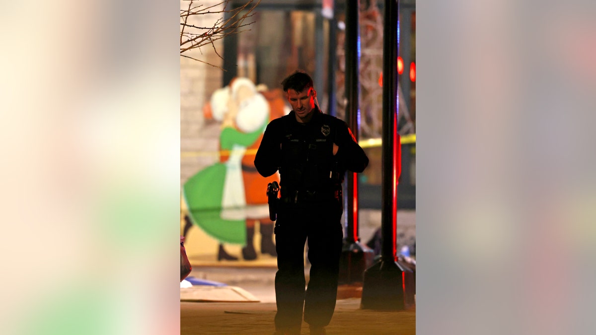 Holiday decorations frame a police officer as he walks in downtown Waukesha after a vehicle plowed into a Christmas parade injuring multiple people on Sunday, Nov. 21, 2021. 
