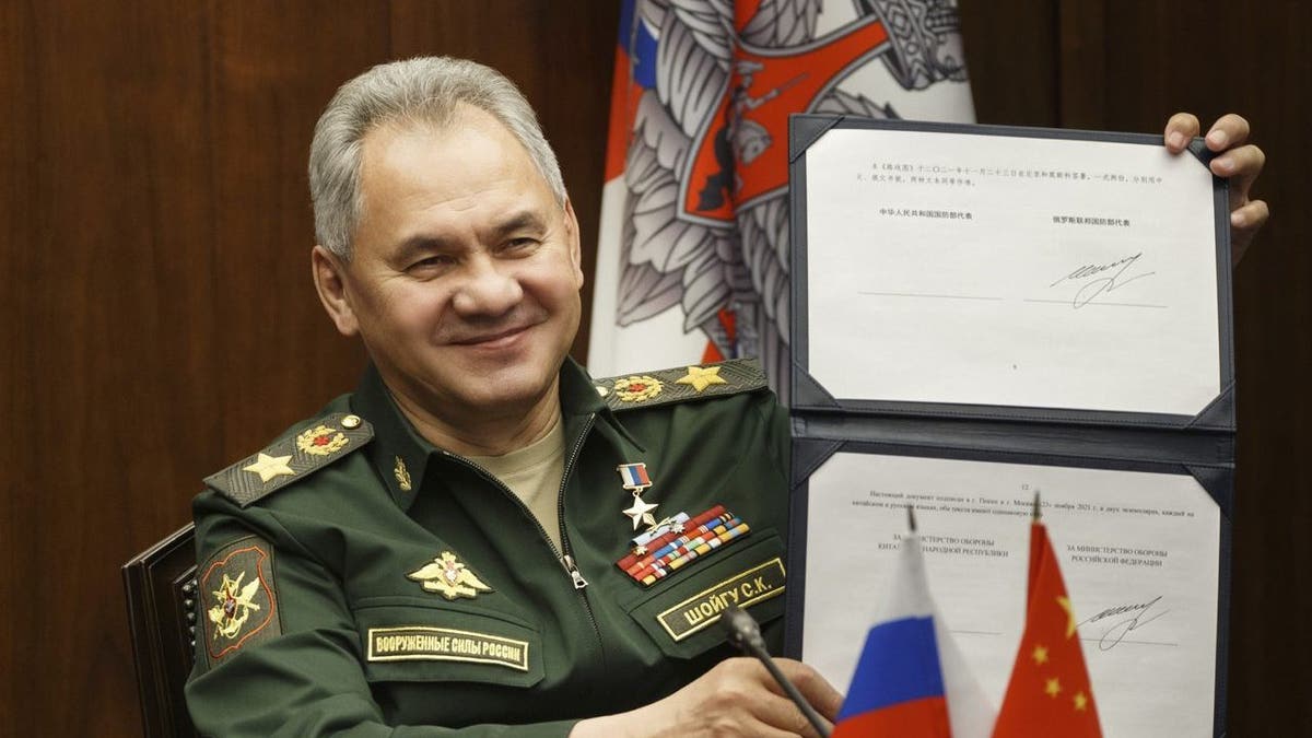 Russian Defense Minister Sergei Shoigu shows his signature under a roadmap for military cooperation between Russia and China during a video call with Chinese Defense Minister Wei Fenghe in Moscow, Russia, Tuesday, Nov. 23, 2021. 