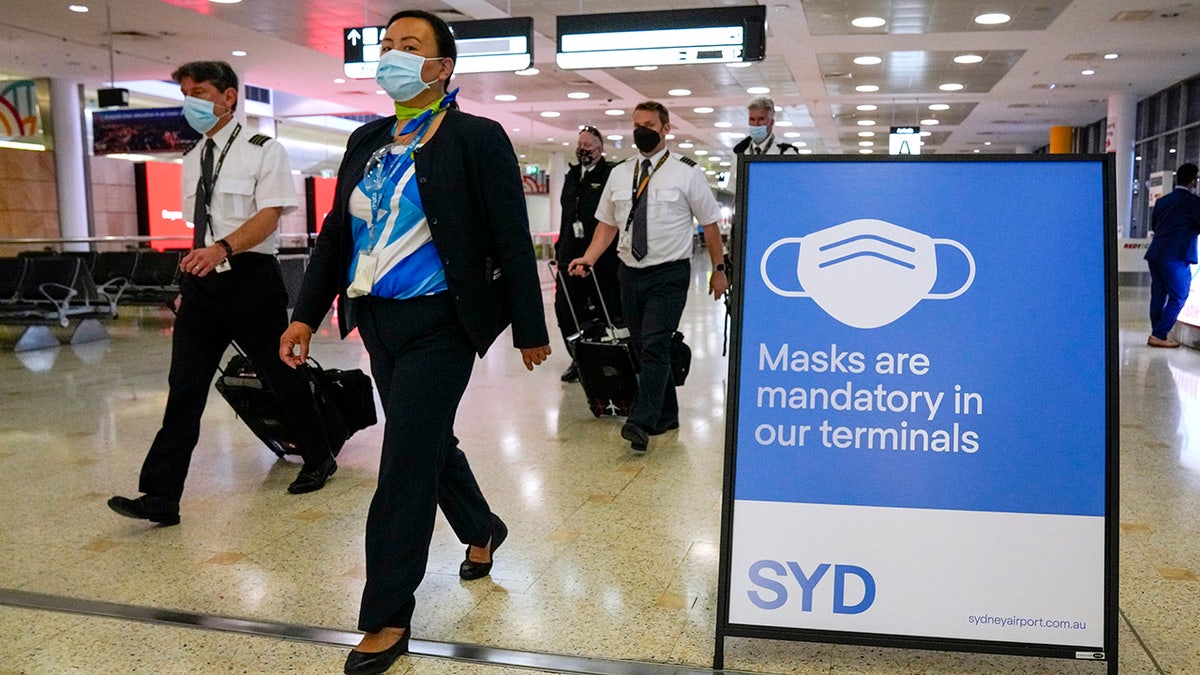 A flight crew walk through the terminal at Sydney Airport, Monday, Nov. 29, 2021. (AP Photo/Mark Baker)