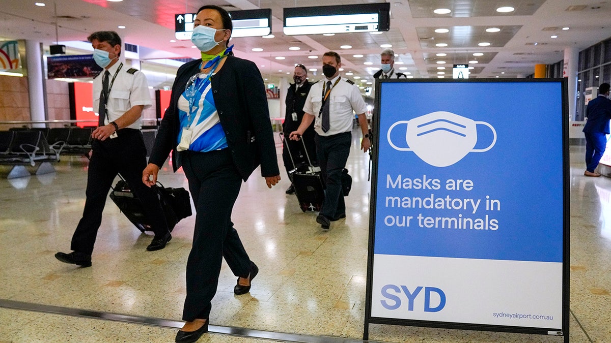 A flight crew walk through the terminal at Sydney Airport, Monday, Nov. 29, 2021. Authorities in Australia said Sunday, Nov. 28, 2021, that two travelers who arrived in Sydney from Africa became the first in the country to test positive for the new variant of the coronavirus, omicron.
