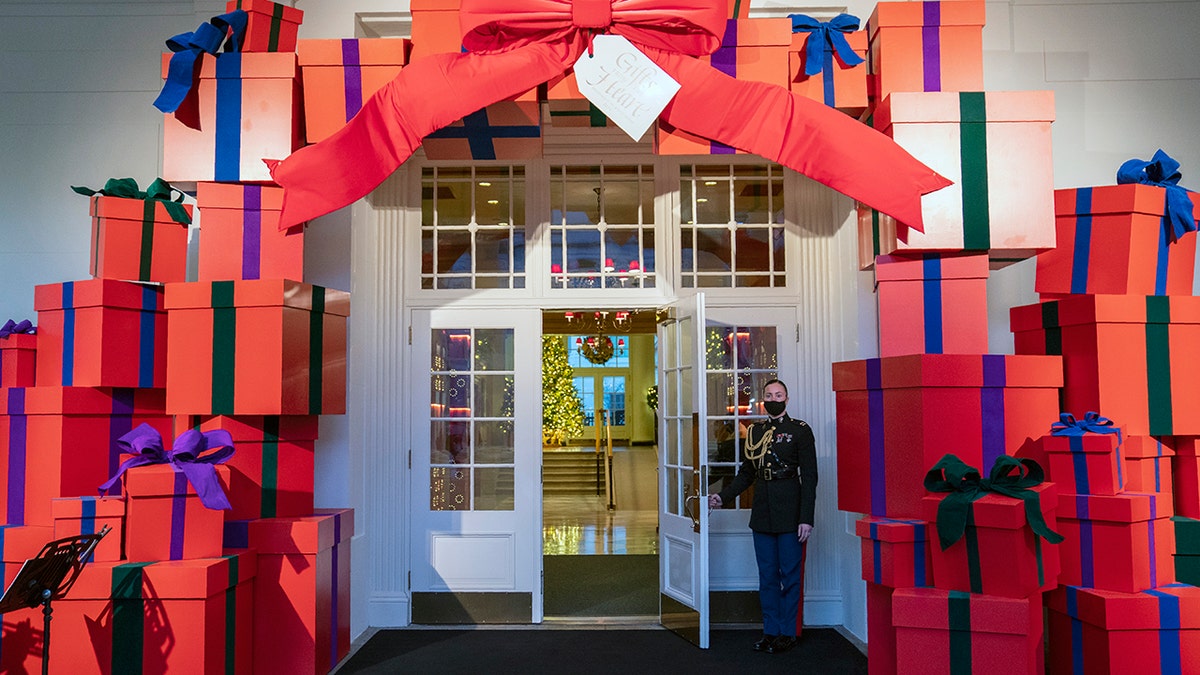 A Marine White House Military social aide holds the door to the East Wing entrance of the White House during a press preview of the White House holiday decorations, Monday, Nov. 29, 2021, in Washington. 