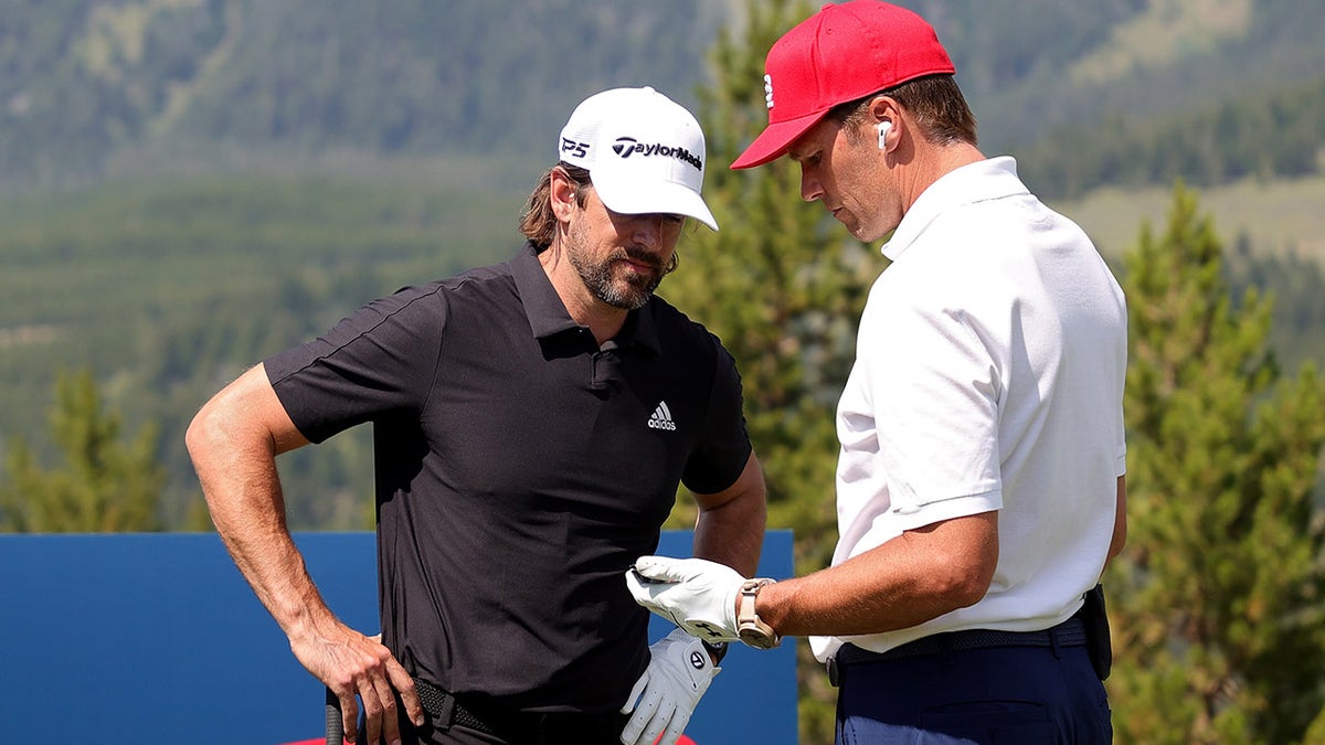 Aaron Rodgers (L) and Tom Brady meet on the first tee during Capital One's The Match at The Reserve at Moonlight Basin on July 06, 2021 in Big Sky, Montana.