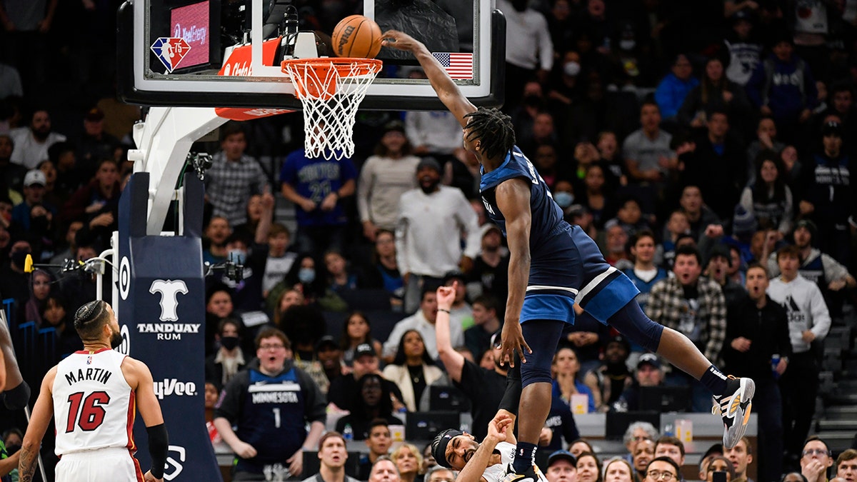 Minnesota Timberwolves guard Anthony Edwards, right, is called for an offensive foul as he leaps over Miami Heat guard Gabe Vincent and dunks the ball while Miami Heat forward Caleb Martin (16) looks on during the second half of an NBA basketball game Wednesday, Nov. 24, 2021, in Minneapolis.