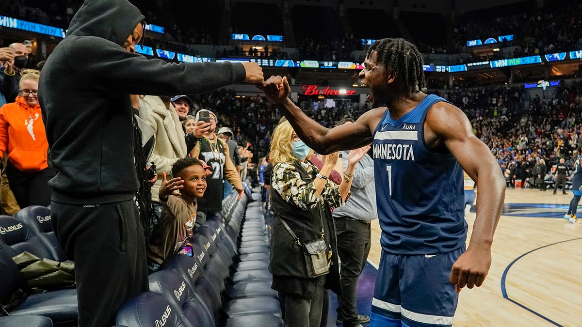Minnesota Timberwolves guard Anthony Edwards celebrates with a fan after defeating the Miami Heat 113-101 during an NBA basketball game Wednesday, Nov. 24, 2021, in Minneapolis.