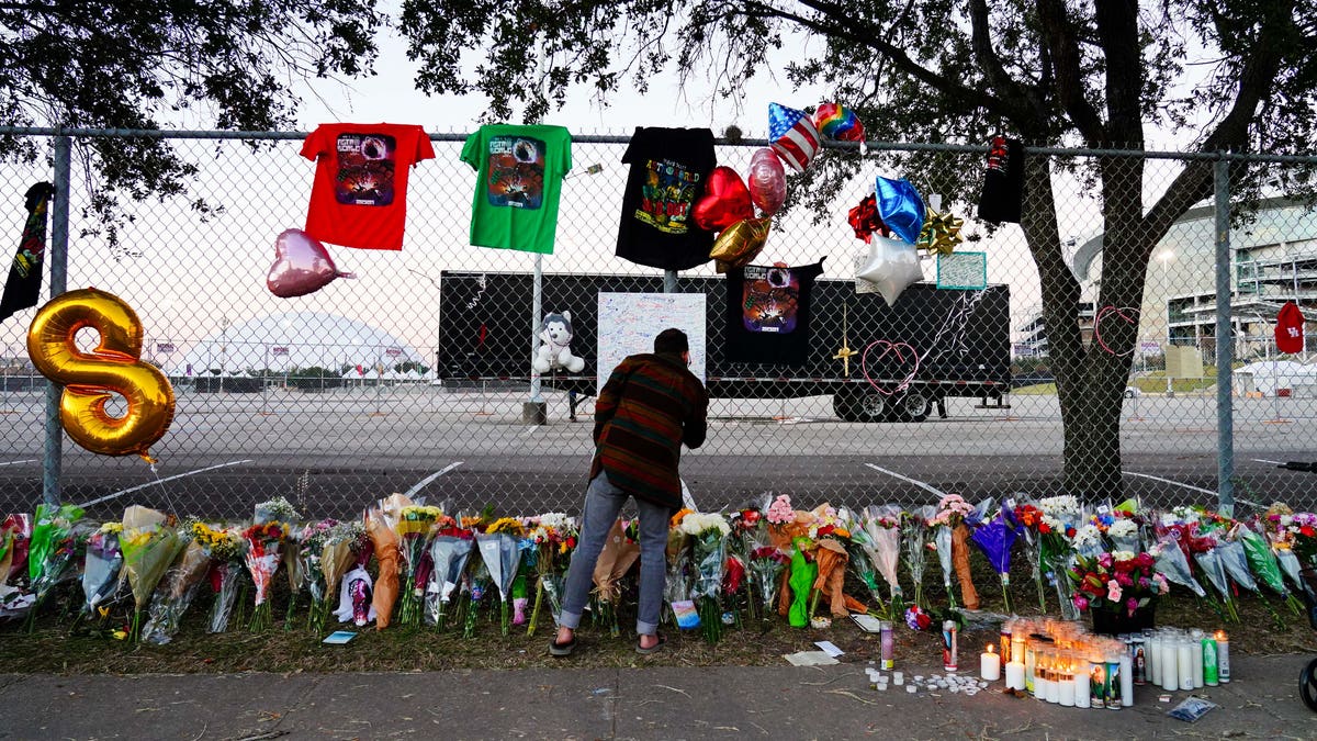 A visitor writes a note at a memorial outside of the canceled Astroworld festival at NRG Park in Houston.