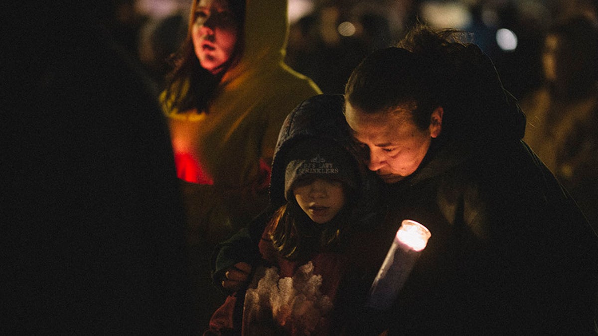 People hold candles and embrace during a vigil in Cutler Park on Nov. 22, 2021, in Waukesha, Wisconsin. (Jim Vondruska/Getty Images)