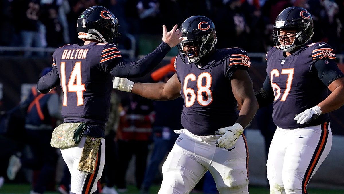 Chicago Bears quarterback Andy Dalton (14) celebrates his touchdown pass tp Darnell Mooney with James Daniels (68) and Sam Mustipher during the second half of an NFL football game against the Baltimore Ravens Sunday, Nov. 21, 2021, in Chicago.