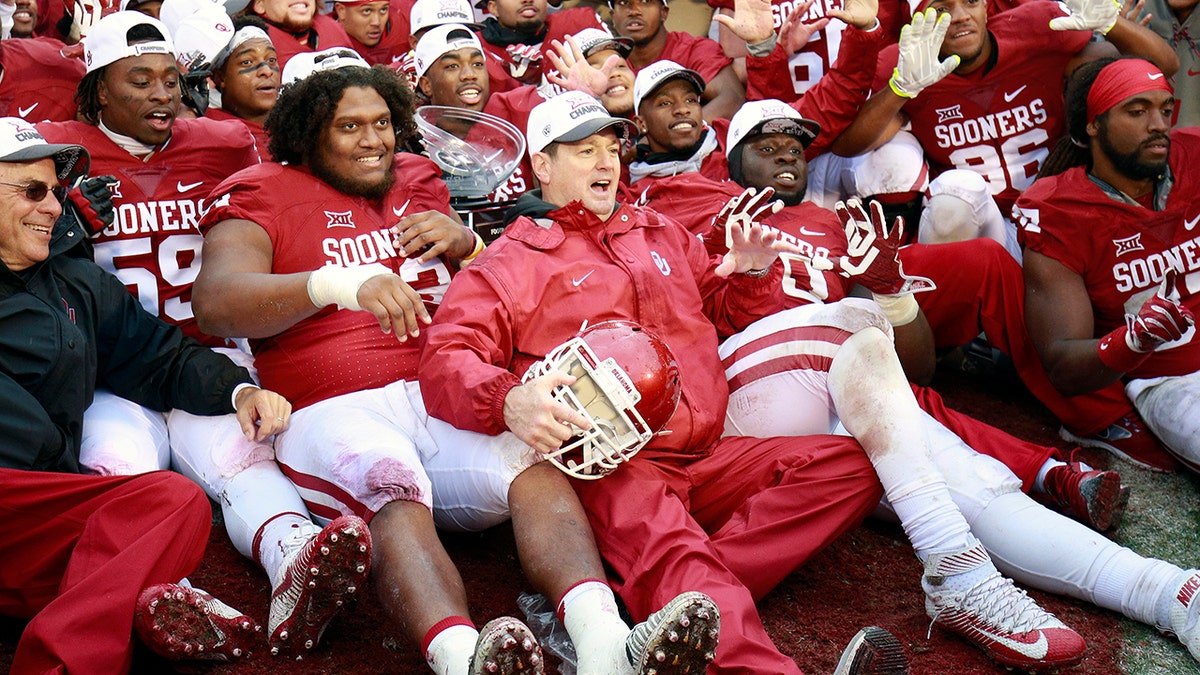 Head Coach Bob Stoops of the Oklahoma Sooners poses for pictures with the team after the game against the Oklahoma State Cowboys December 3, 2016 at Gaylord Family-Oklahoma Memorial Stadium in Norman, Oklahoma.