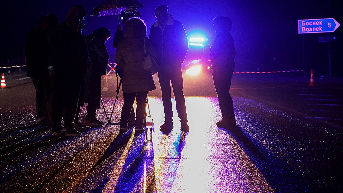 Members of the media stand near a police car, close to the site where at least 45 people were killed when a bus with North Macedonian plates caught fire on a highway, near the village of Bosnek, in Bulgaria November 23, 2021. REUTERS/Stoyan Nenov