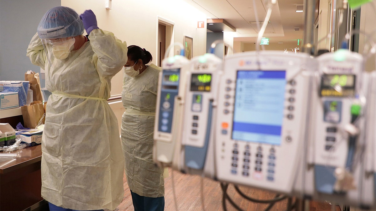 ICU nurse Samantha Lazzara, left, and Judith Mclean, right, a patient care technician, put on PPE gear before entering a COVID-19 patient's room in the ICU unit at Northwestern Medicine Lake Forest Hospital on Friday, Oct. 1, 2021, in Lake Forest, Illinois.?