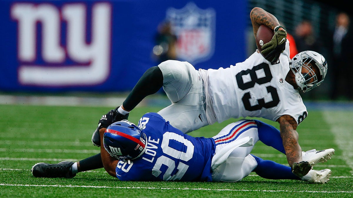 The New York Giants' Julian Love (20) tackles the Las Vegas Raiders' Darren Waller (83)