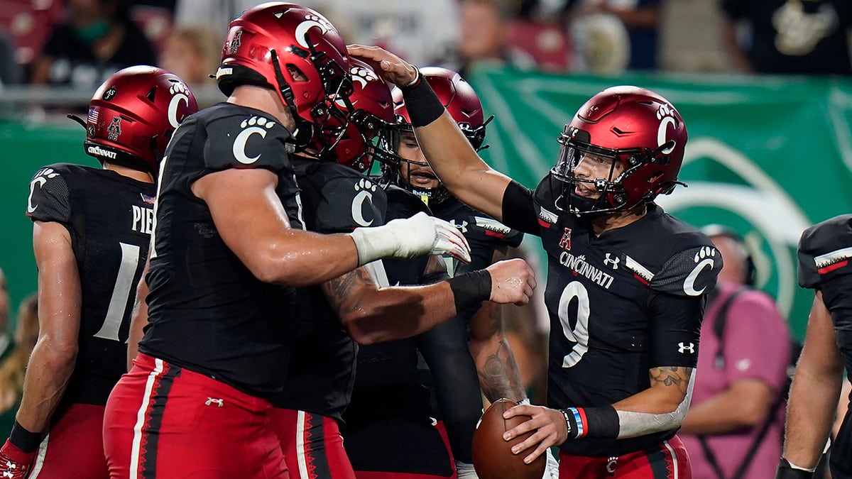 Cincinnati quarterback Desmond Ridder (9) celebrates with teammates after his 13-yard touchdown run against South Florida during the first half of an NCAA college football game Friday, Nov. 12, 2021, in Tampa, Fla.