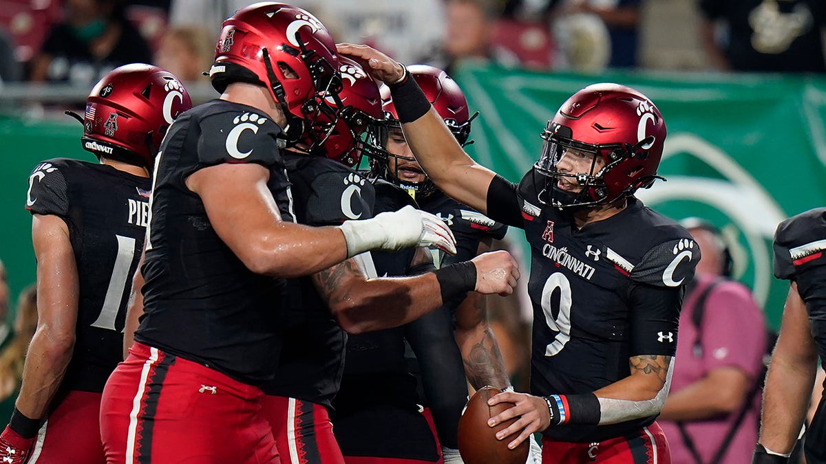 Cincinnati quarterback Desmond Ridder (9) celebrates with teammates after his 13-yard touchdown run against South Florida during the first half of an NCAA college football game Friday, Nov. 12, 2021, in Tampa, Fla.