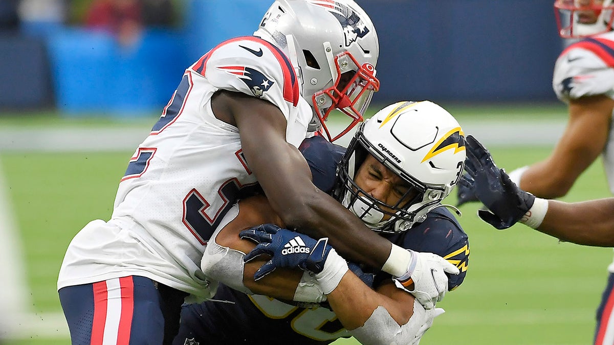 Austin Ekeler of the Los Angeles Chargers runs with the ball while being tackled by Devin McCourty of the New England Patriots in the fourth quarter at SoFi Stadium on Oct. 31, 2021, in Inglewood, California.
