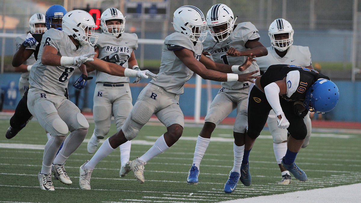 LOS ANGELES, CA - APRIL 9, 2021: Five  Reseda defenders team up to force  Crenshaw wide receiver Centrell Wise (10) out of bounds in the first half at Crenshaw High School on April 9, 2021 in Los Angeles, California.(Gina Ferazzi / Los Angeles Times via Getty Images)
