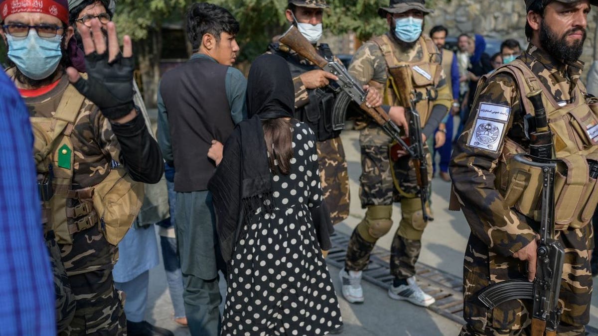 A Taliban fighter (left) makes a hand gesture asking the photojournalists to stop covering a demonstration by women protesters in Kabul, Afghanistan, on Sept. 30, 2021. 